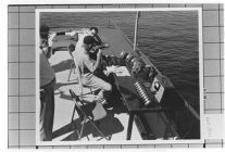 Speed Boats.  Three men sitting and a desk on dock
